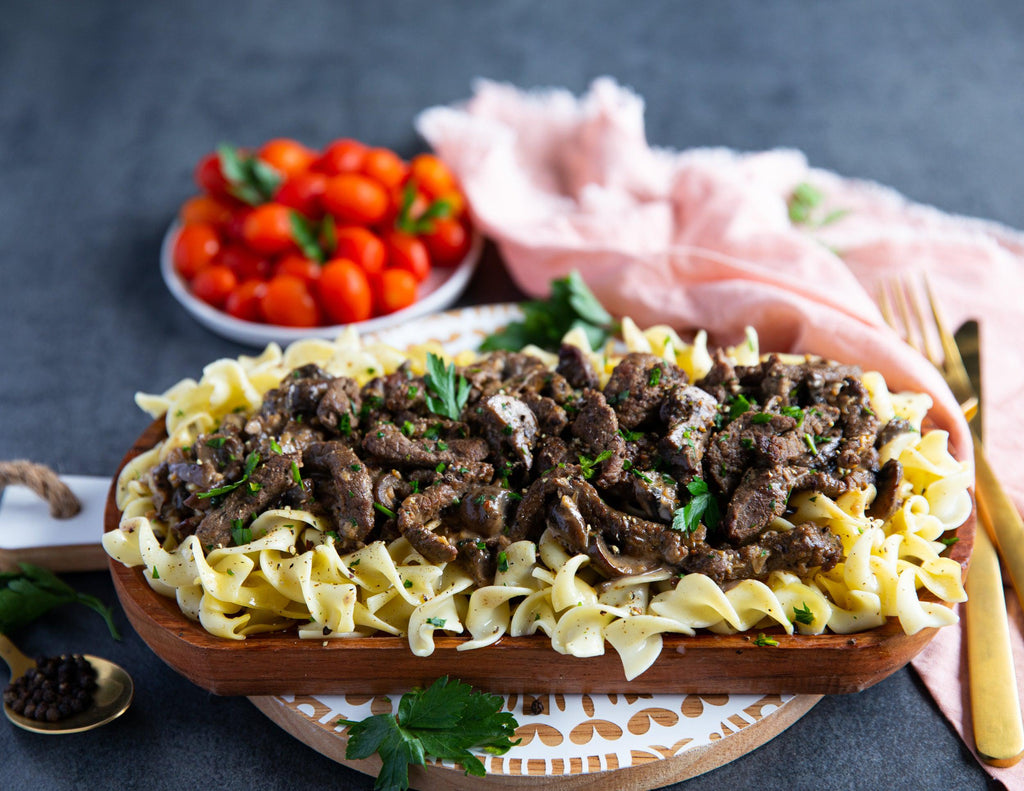 Thinly sliced steak on bed of egg noodles with mushroom sauce