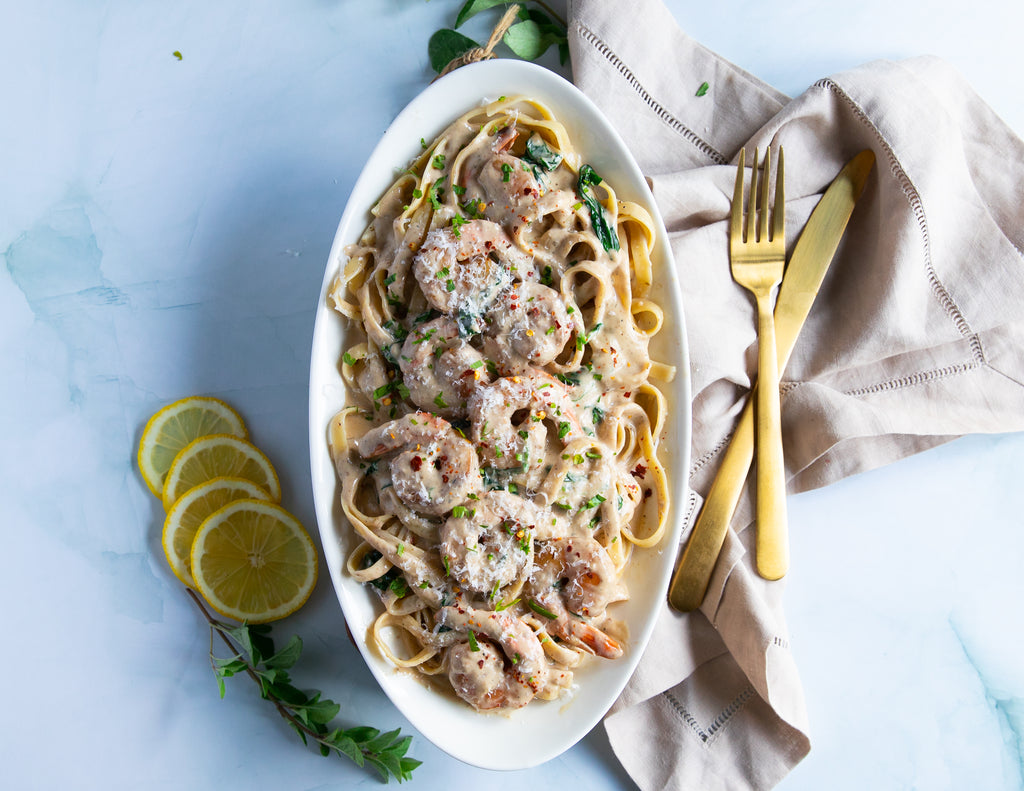 Large cooked shrimp on a bed of fettuccine with cream sauce and parmesan