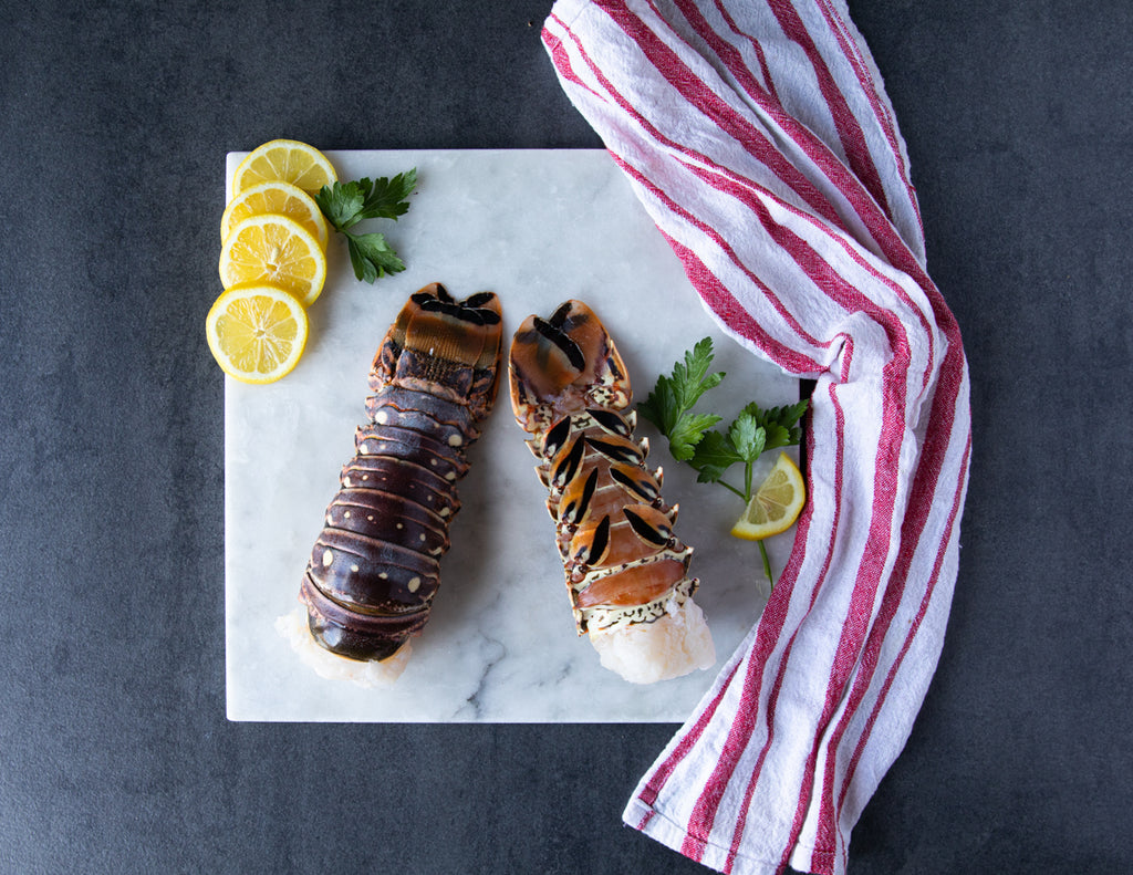 Two Raw Sealand Quality Foods Warm Water Lobster Tails on a Marble Slab