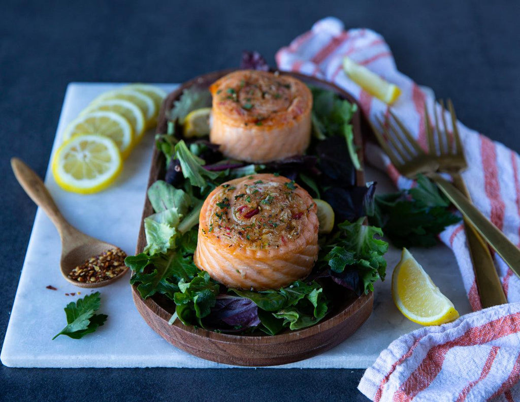 Crab stuffed salmon pinwheels on a bed of greens with lemon