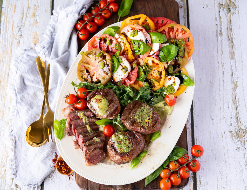 Image of bacon wrapped tenderloin steak with a side Caprese salad