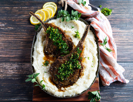 French cut veal chops over mashed potatoes, with sauce and garnish