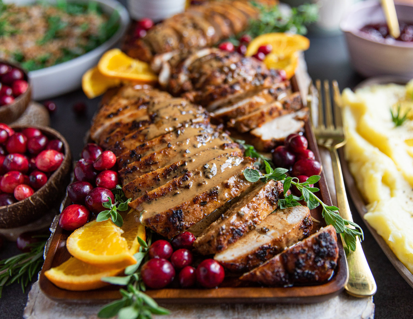 Sealand Garlic Herb Turkey Tenderloin and Gravy sliced on a serving platter with fresh cranberries
