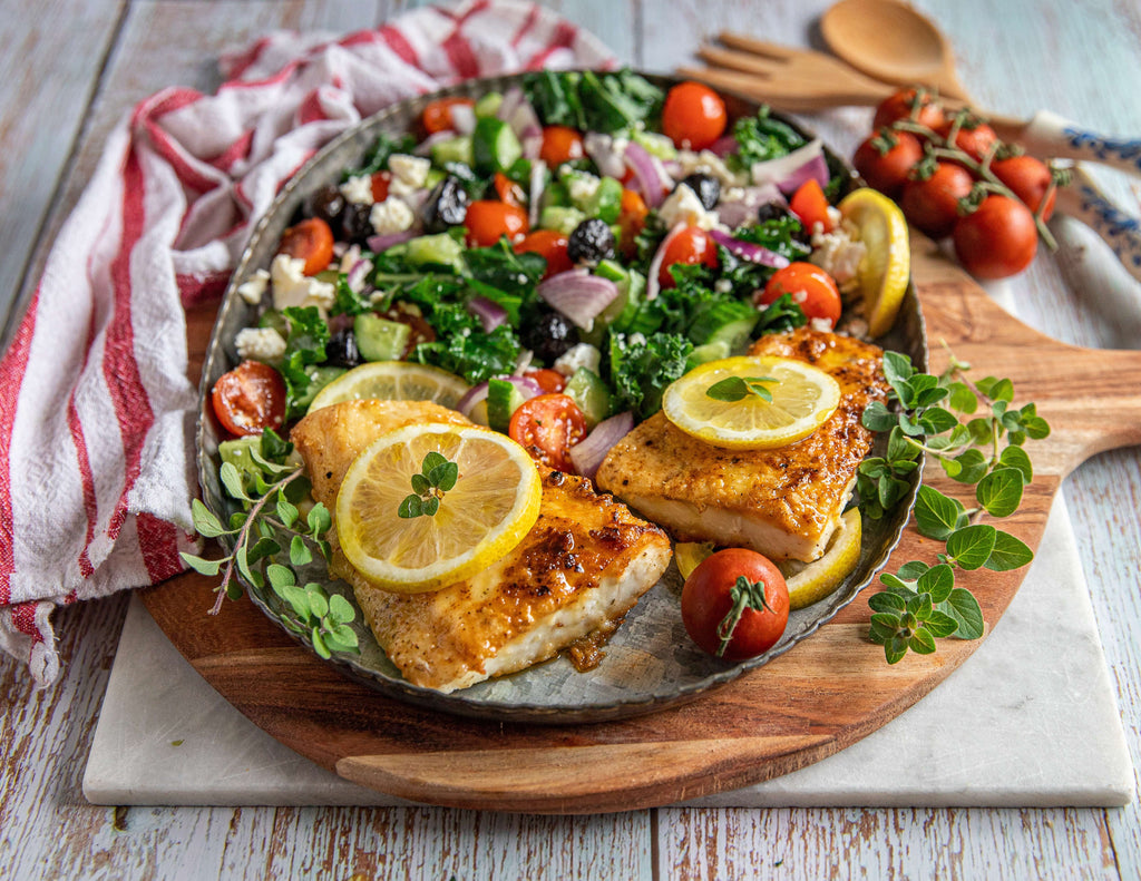 Halibut fillets with lemon slices, cherry tomatoes and fresh vegetables