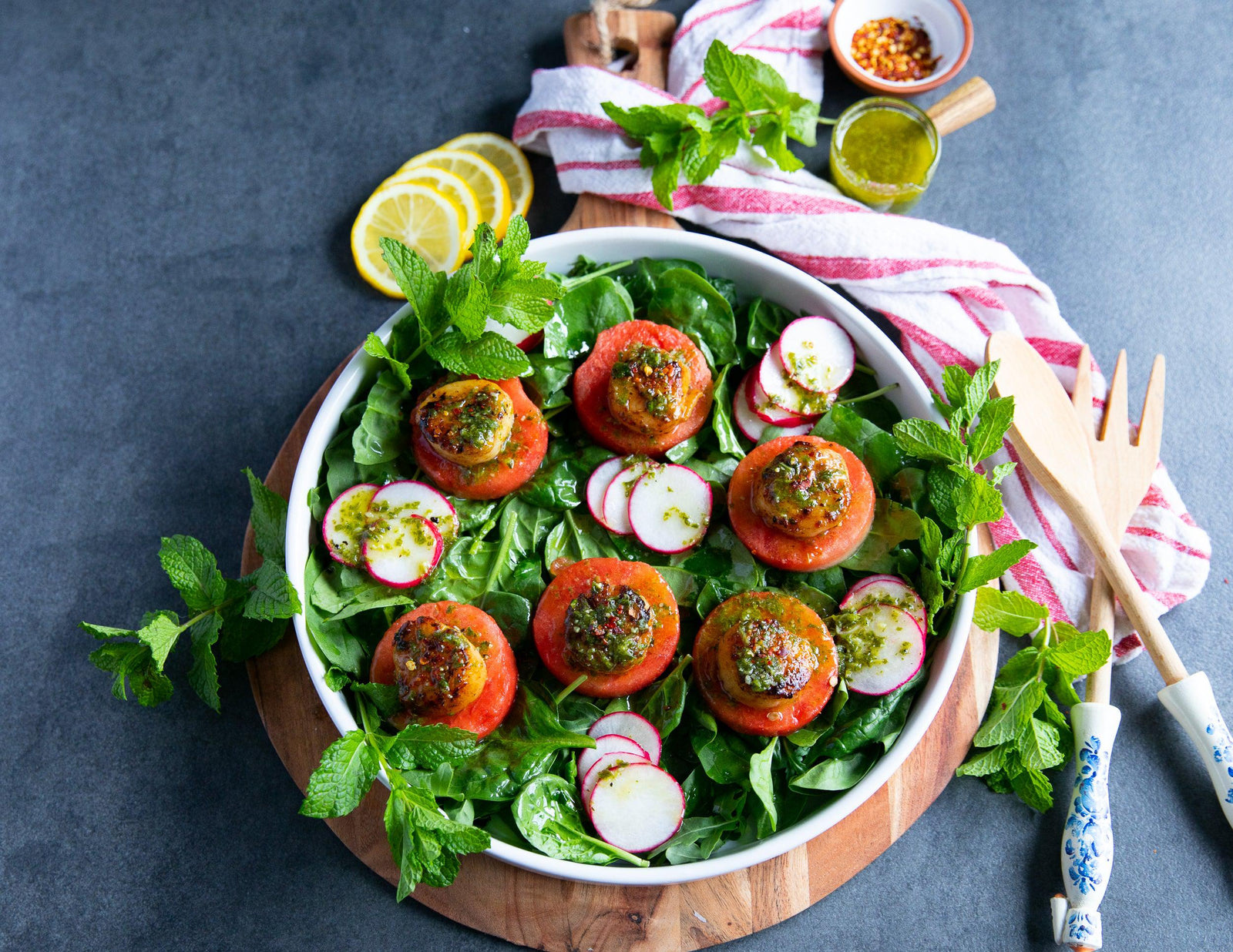 Fresh scallops on watermelon slices over a bed of arugula with sliced radishes