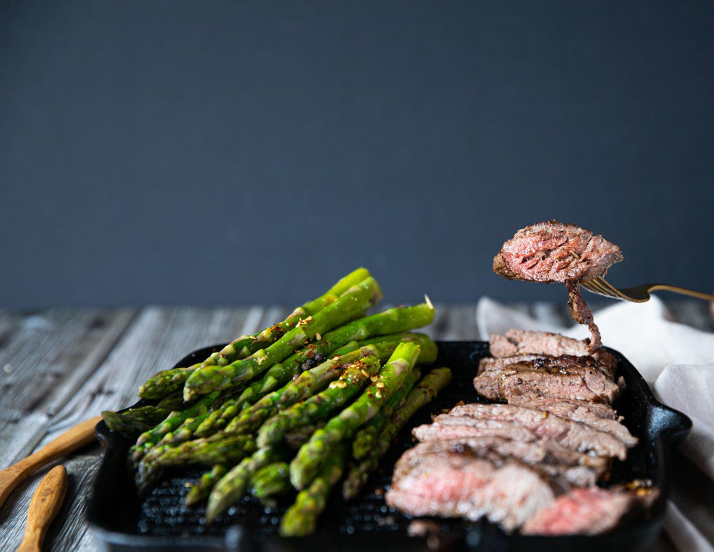 Sealand's Bavette Steaks on a cast iron skillet served with fresh asparagus.