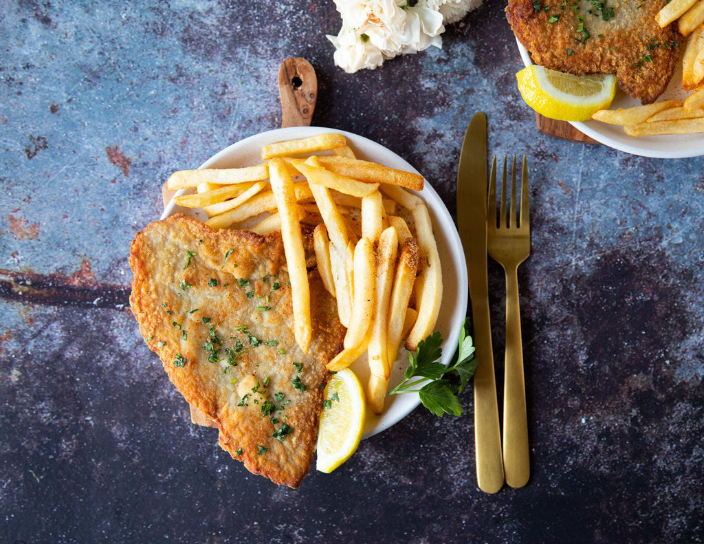 Sealand's Breaded Pork Schnitzels served with a side of fries and a lemon wedge.