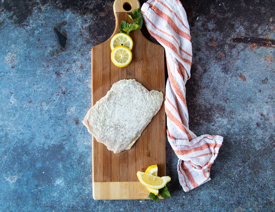 Single Frozen Breaded Pork Schnitzel from Sealand Quality Foods on a Wooden Cutting Board