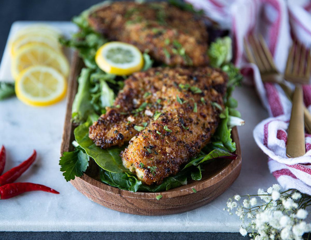 Caribbean Crusted Tilapia Fillets on a wooden platter with mixed greens.