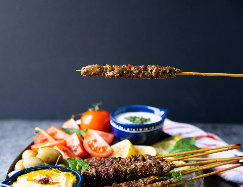 Sealand's Lamb Spiedini skewered and served on a platter with fresh vegetables and creamy dipping sauces.