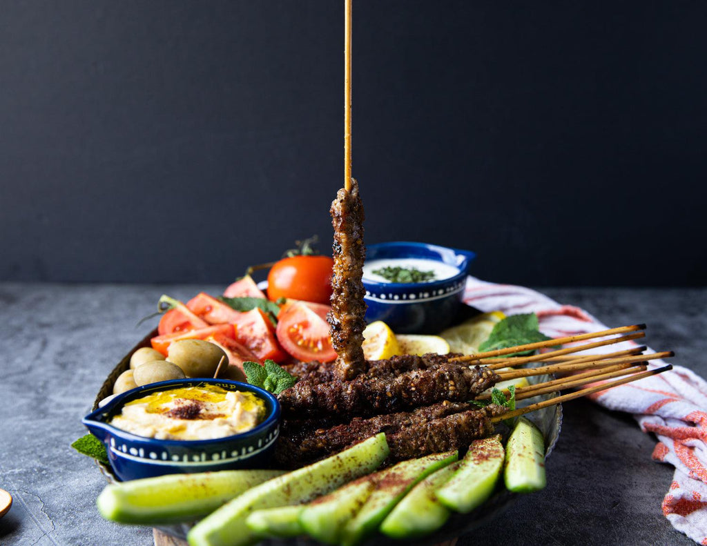 Sealand's Lamb Spiedini skewered and served on a platter with fresh vegetables and creamy dipping sauces.