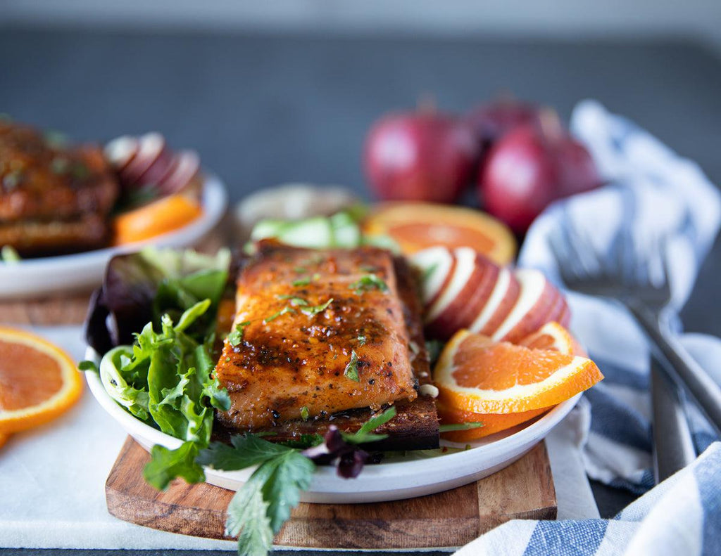Sealand's Personal Cedar Plank Salmon on a bed of greens and a side of fresh fruit.