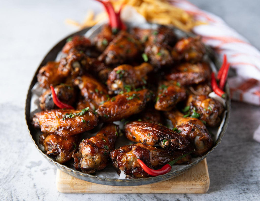 Sealand Quality Foods' Roaster Style Chicken Wings served on a platter with bird's eye chili peppers.
