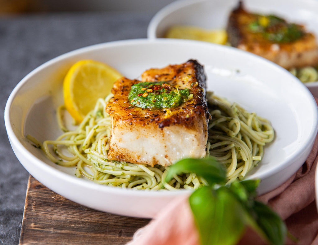 A Chilean Sea Bass on a bed of noodles and topped with basil pesto from Sealand Quality Foods.