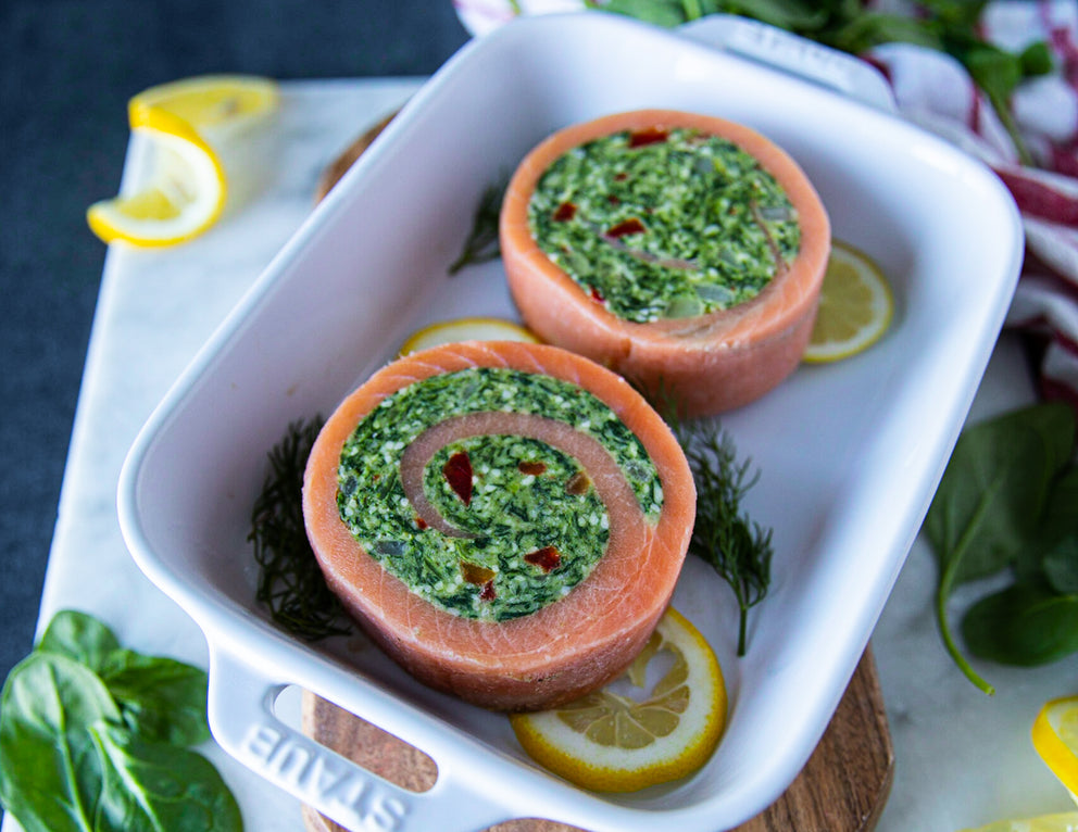 Two Frozen Sealand Spinach Stuffed Salmon Pinwheels in a Baking Dish with Lemons
