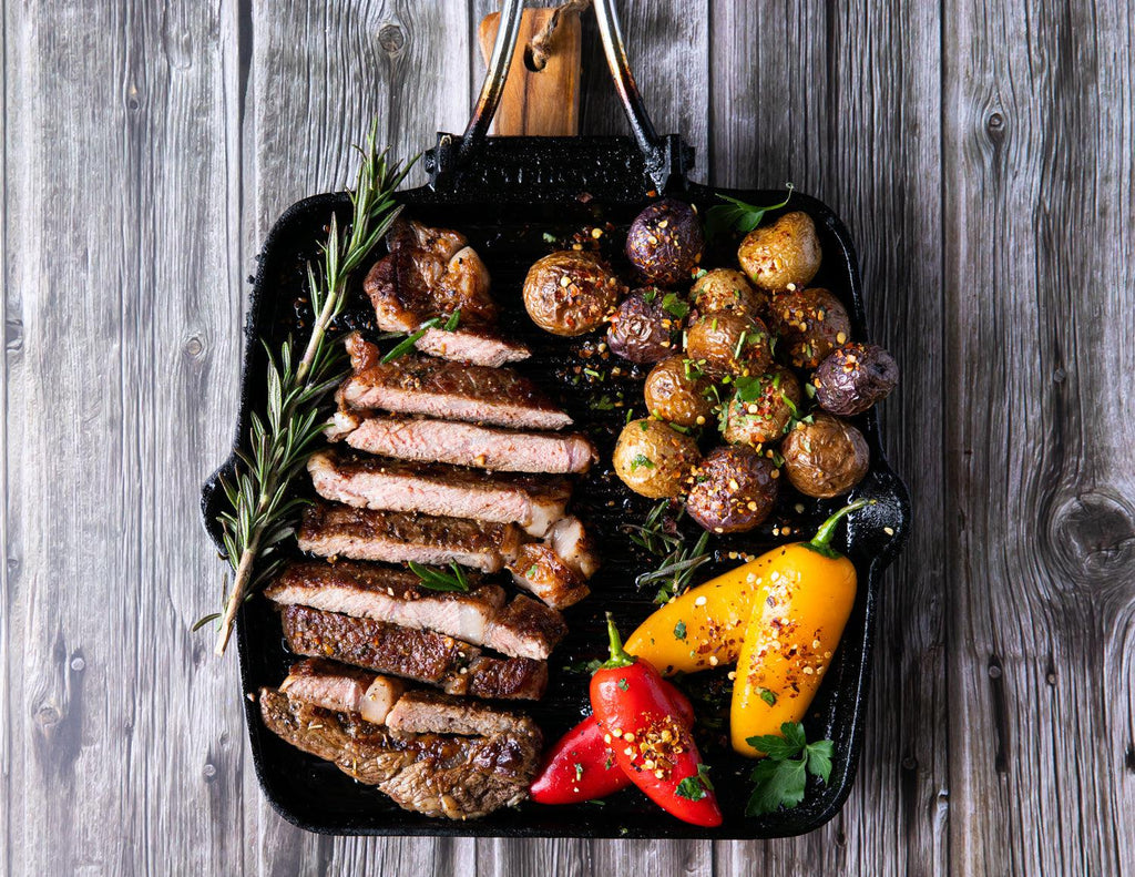 Sealand Quality Foods' sliced Wagyu Ribeye Steaks seared on a cast iron skillet with peppers and potatoes.