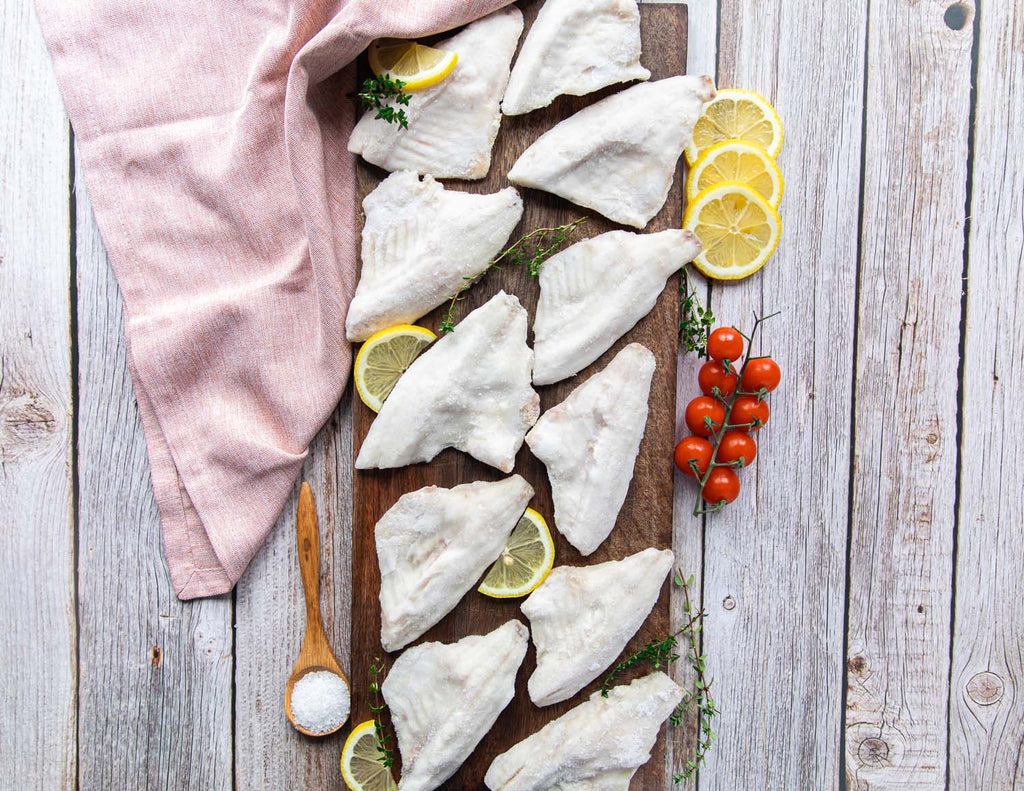 Sealand's Wild Caught Ontario White Perch Fillets frozen and placed on a wooden plank with lemon slices.